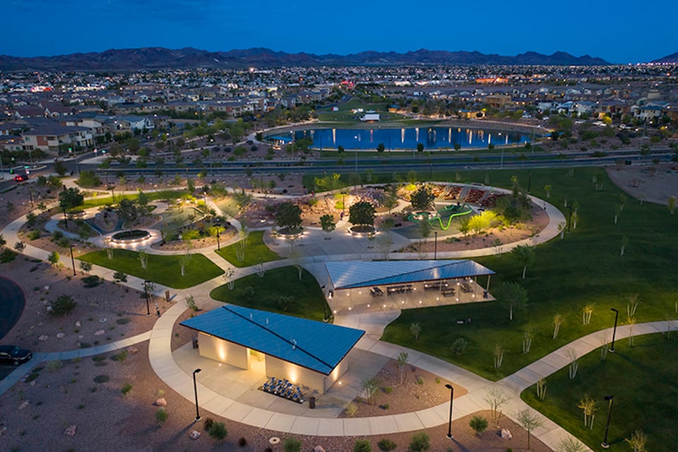 A building with a pool in the middle of a field with a city in the background.