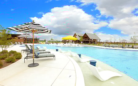 A pool with lounge chairs and umbrellas by it.