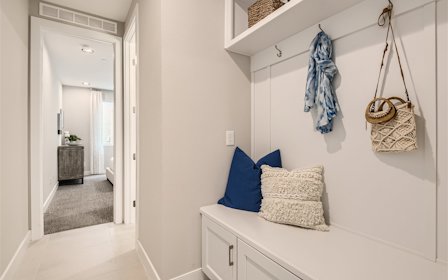A room with white walls and a white shelf with a blue pillow.