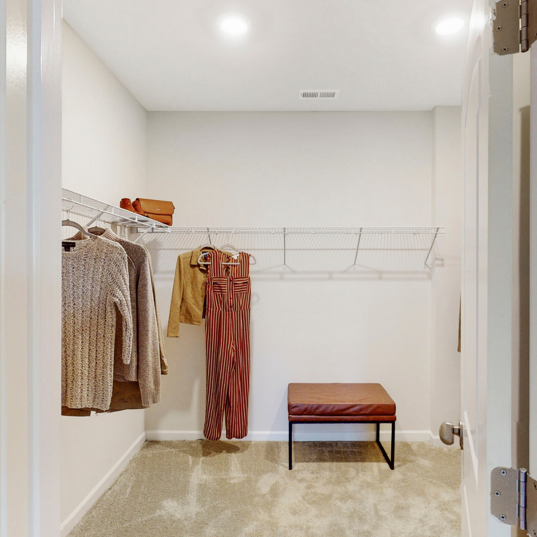 Spacious walk-in closet with seating.