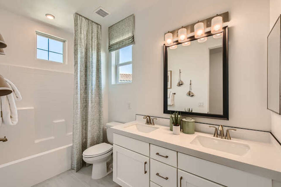A bathroom with a sink toilet and mirror.