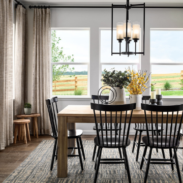 Charming dining area boasting dramatic overhead lighting, a wooden table, large windows and inspired floral décor. 