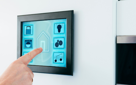 A hand holding a small square object.