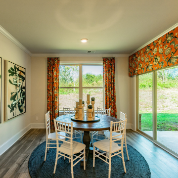 Charming dining area boasting large windows with colorful curtains. 