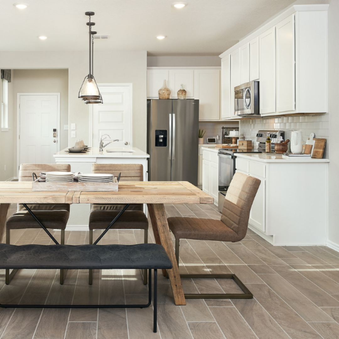 Casual dining area featuring a rustic wood table overlooking a well-appointed white kitchen with wood accents.