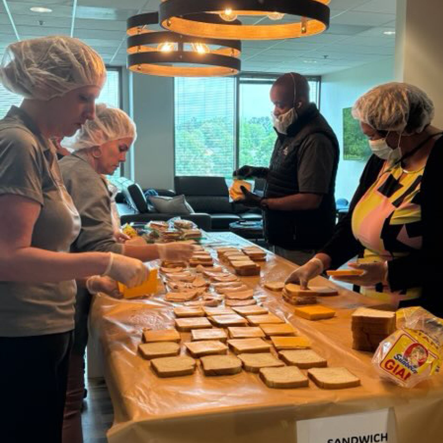 A group of people preparing sandwiches.