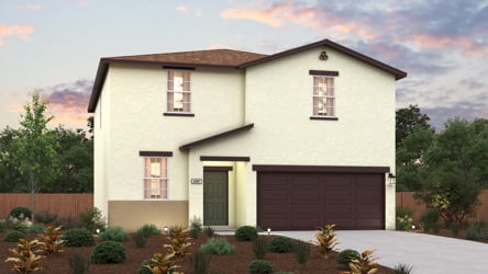 A house with a garage and bushes in front of it.