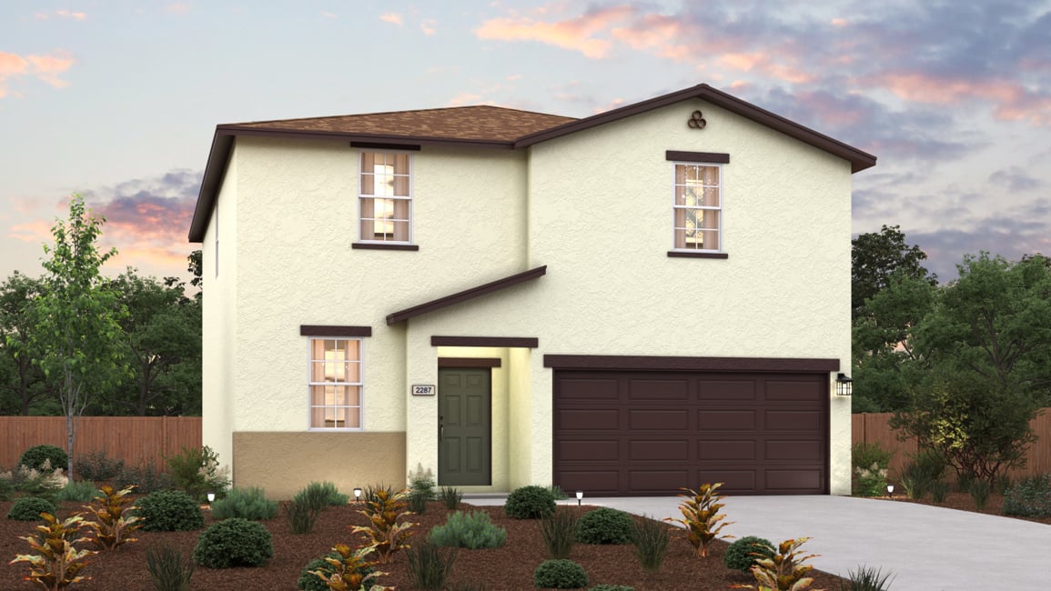 A house with a garage and bushes in front of it.