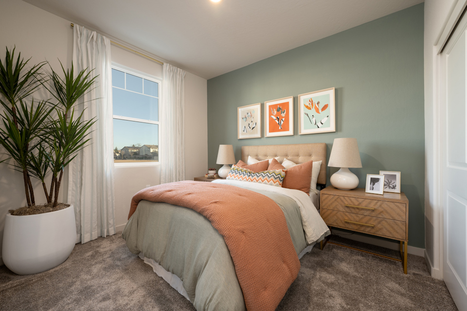 A bedroom with a bed and a plant.