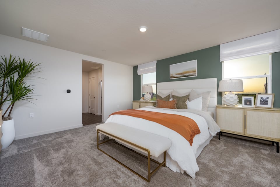 A large bedroom with a bed and a bench.