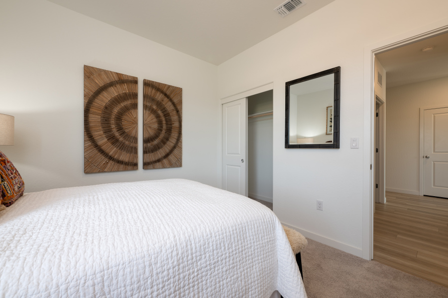 A bedroom with a bed and a mirror.