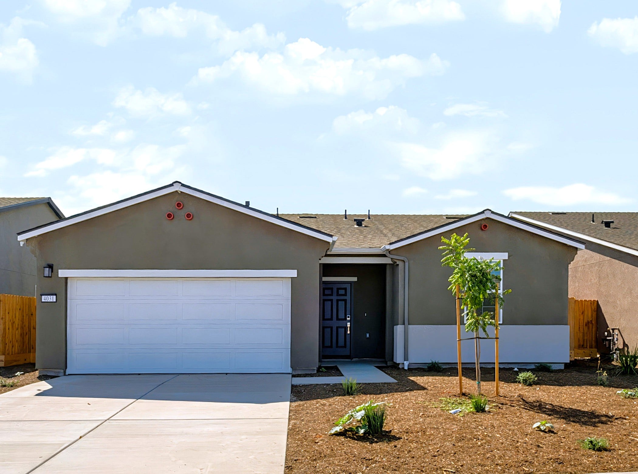 A building with garages and a tree in the front.