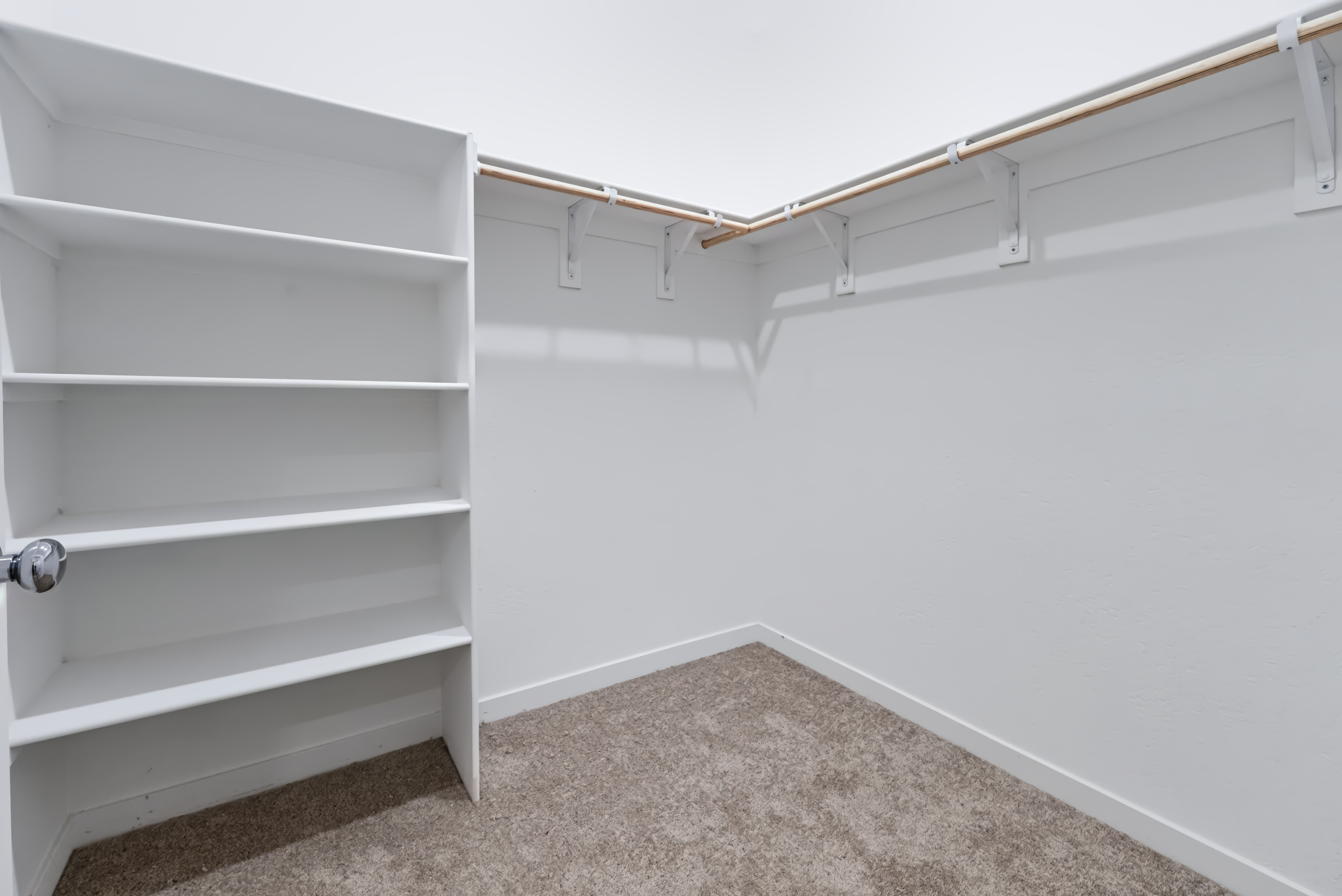 A white shelf with a metal bar.