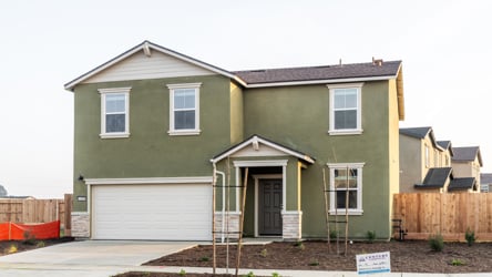 A green house with a garage.
