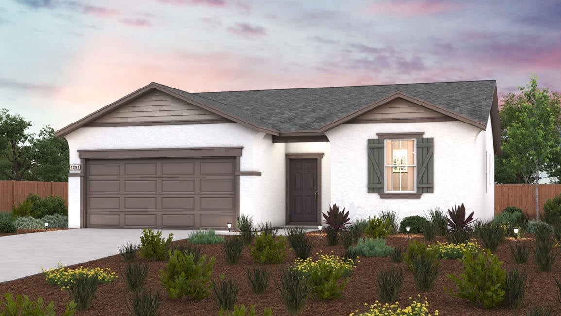 A house with a garage and bushes in front of it.