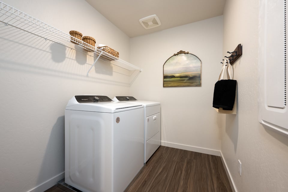 A laundry room with a mirror and a shelf.