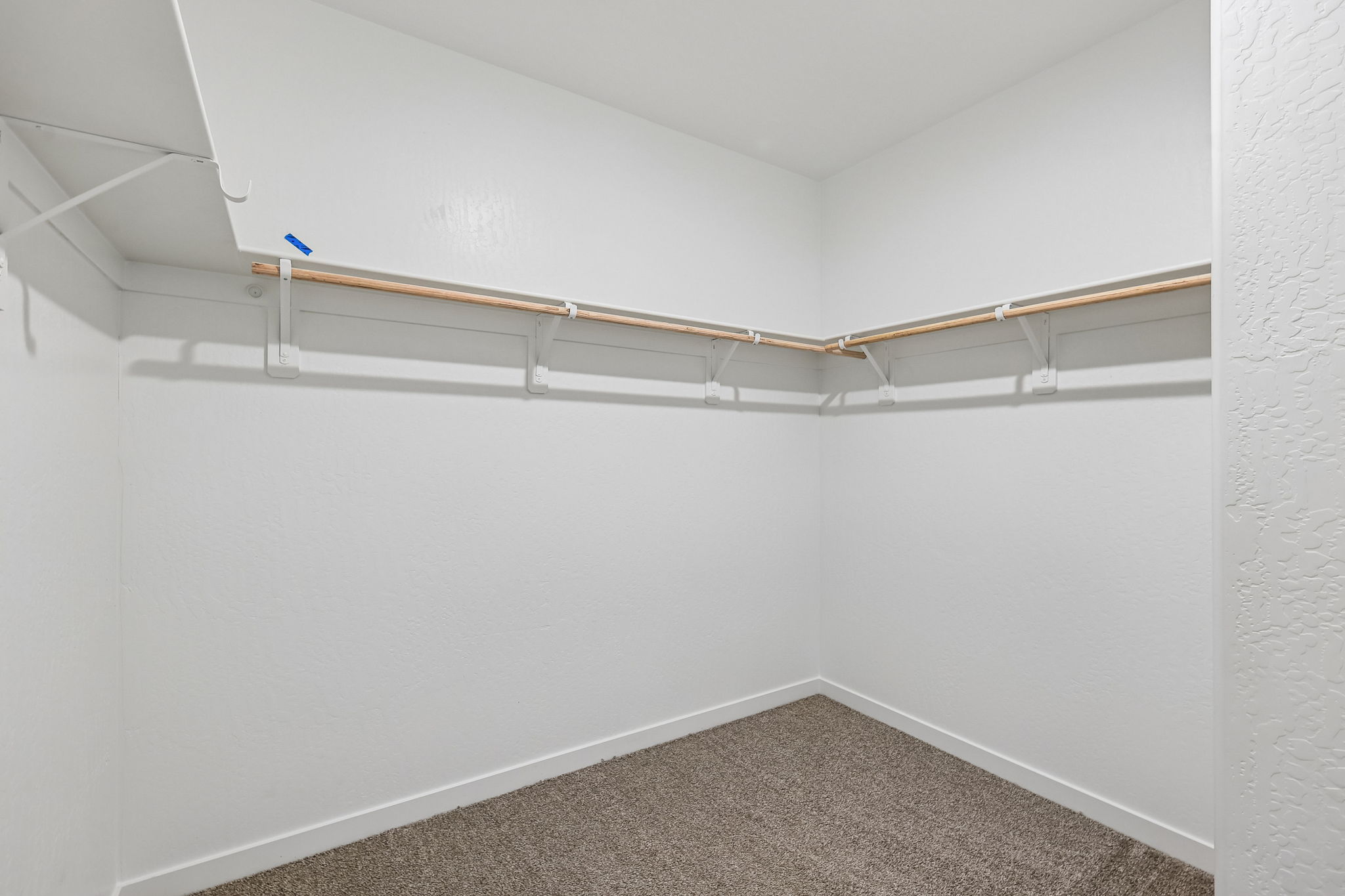 A white room with a carpet and a wood railing.