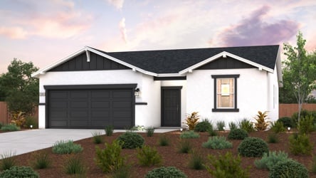 A house with a garage and bushes in front of it.