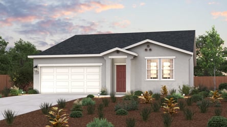 A house with a garage and bushes in front of it.