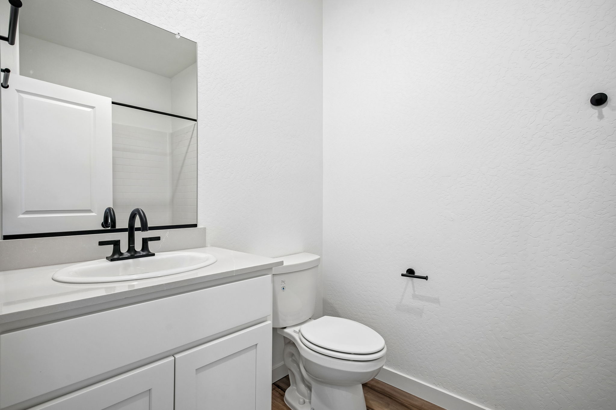 A bathroom with a sink toilet and mirror.