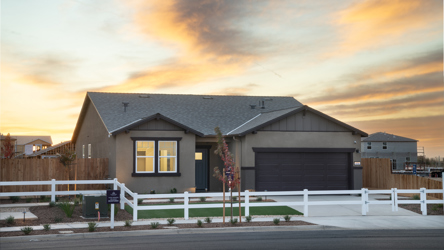 A house with a garage and a fence in front of it.