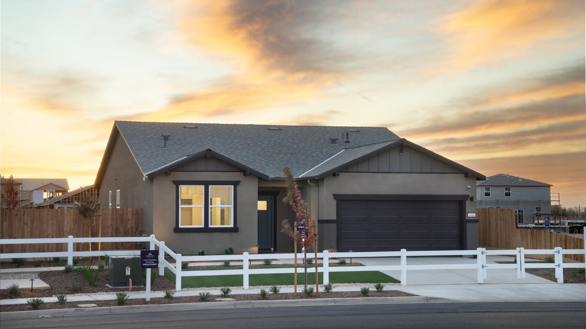 A house with a garage and a fence in front of it.