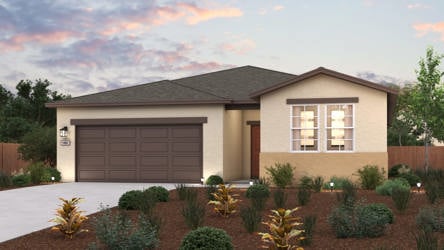 A house with a garage and bushes in front of it.