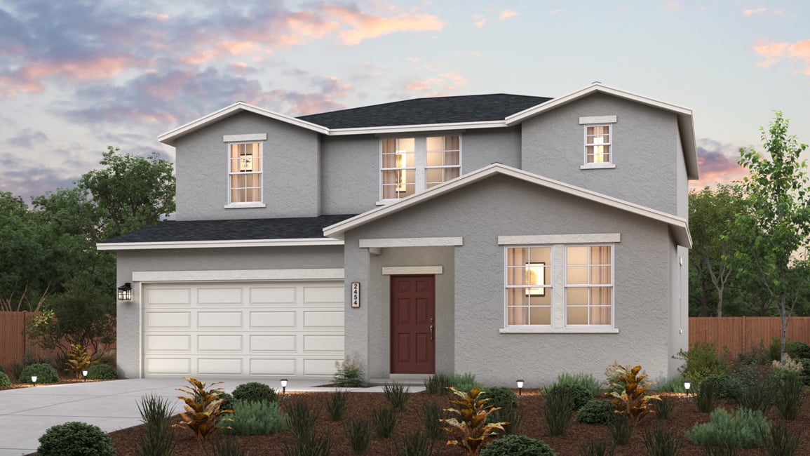 A house with a garage and bushes in front of it.