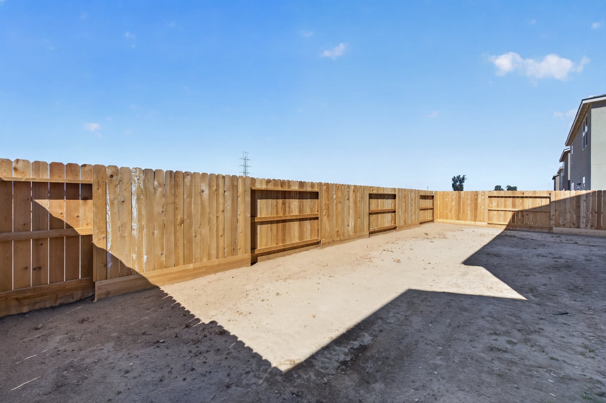 A wooden fence in a dirt lot.
