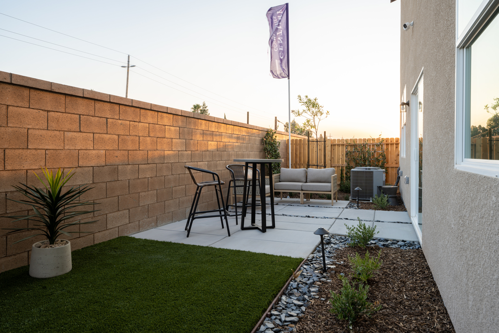 A backyard with a brick wall and a table and chairs.