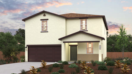 A house with a garage and bushes in front of it.