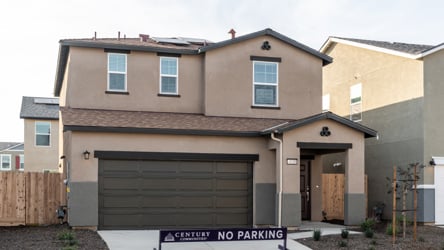 A house with garages and a sign in front of it.