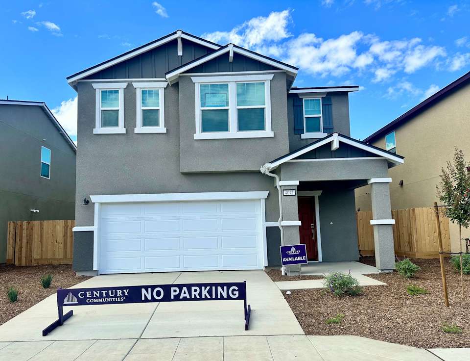 A house with garages and a sign in front of it.