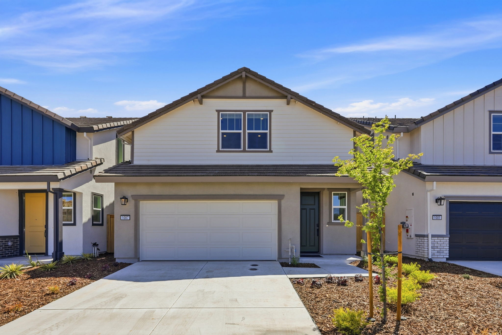 A house with garages and a tree in the front.