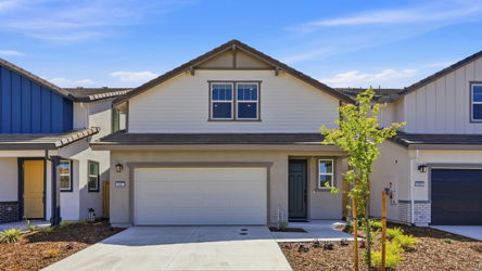 A house with garages and a tree in the front.