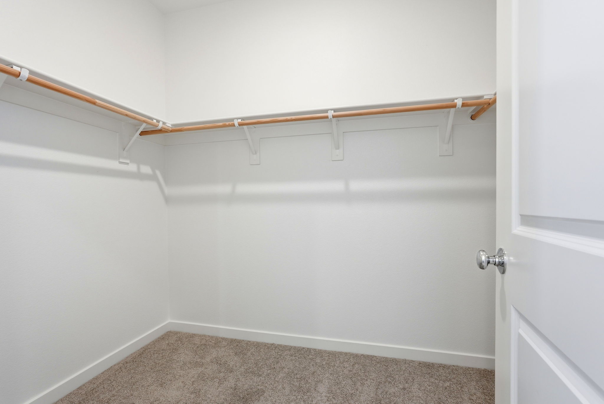 A white wall with a brown carpet.