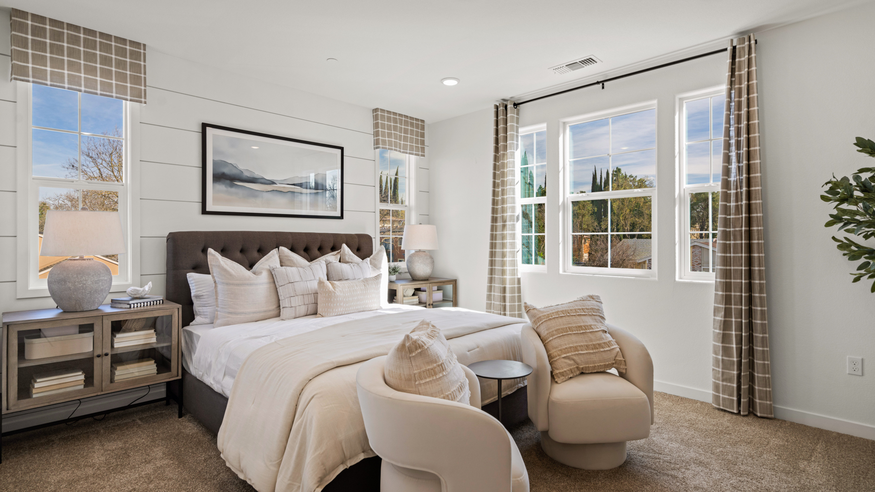 A bedroom with a bed and chairs.