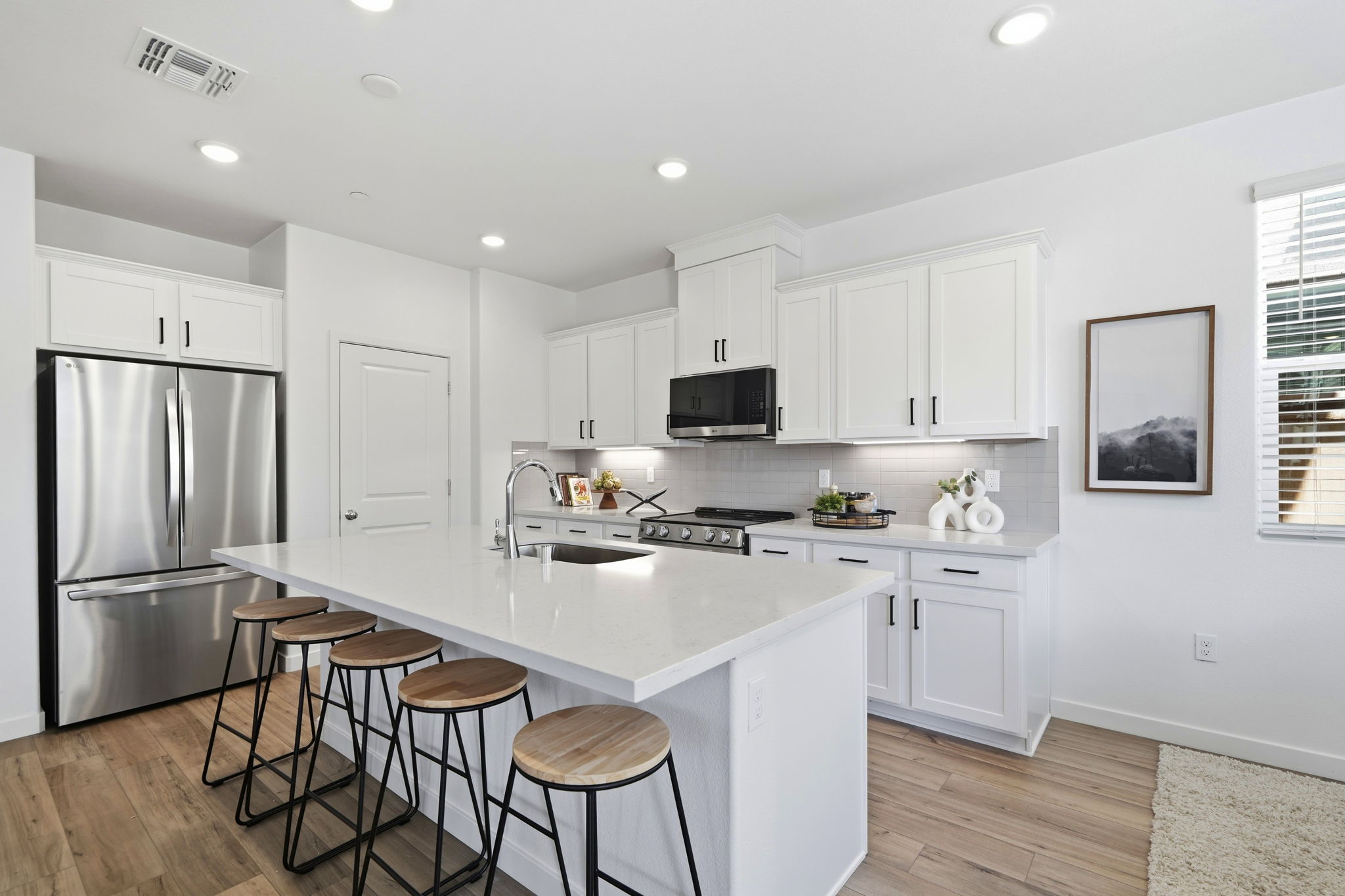 A kitchen with stools and a refrigerator.