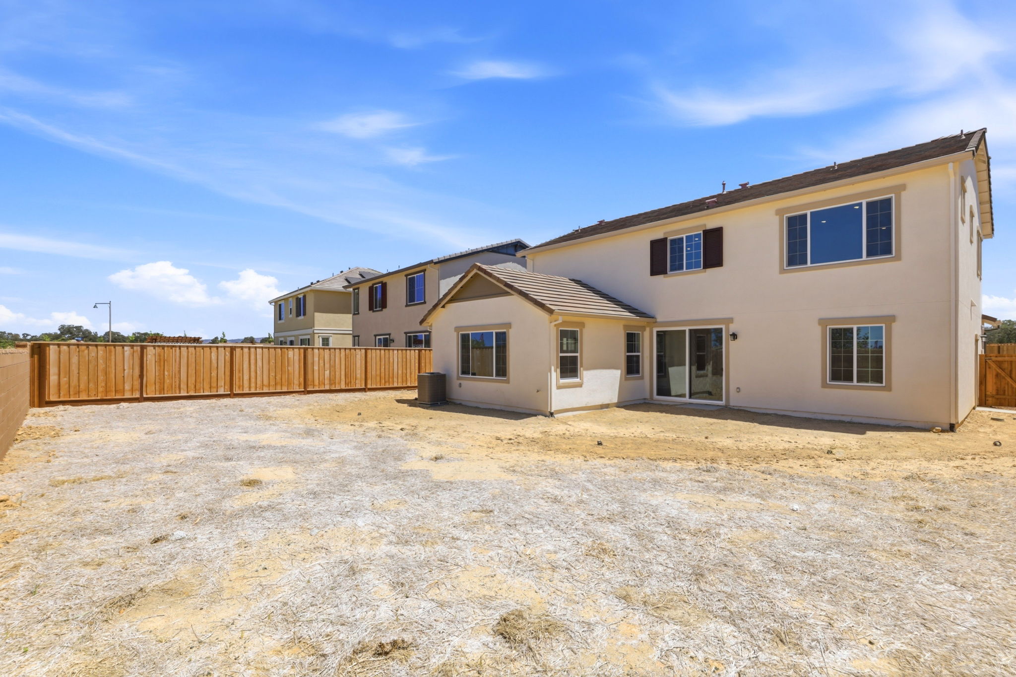 A house with a fence and dirt in front of it.