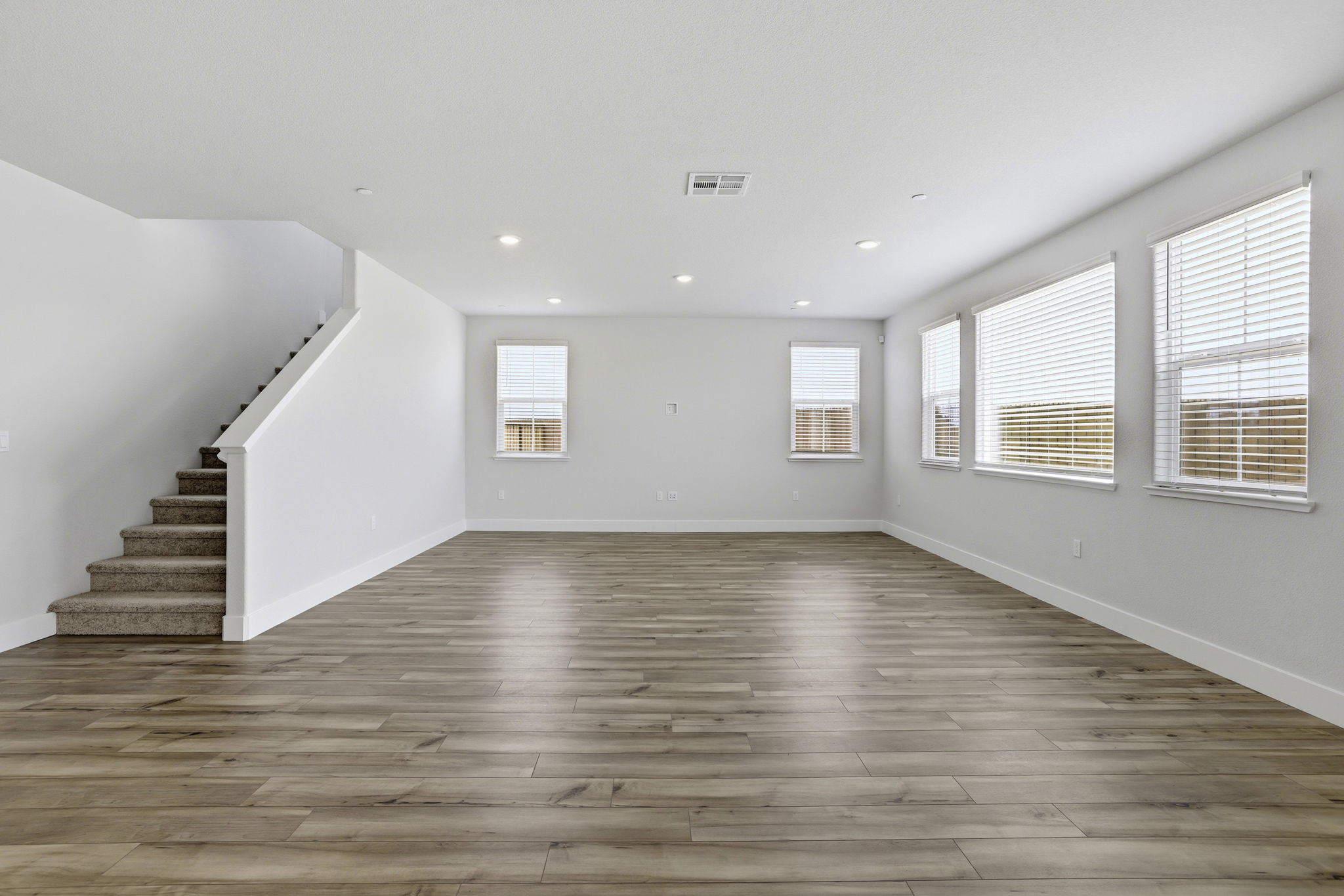 A large empty room with a wood floor and windows.