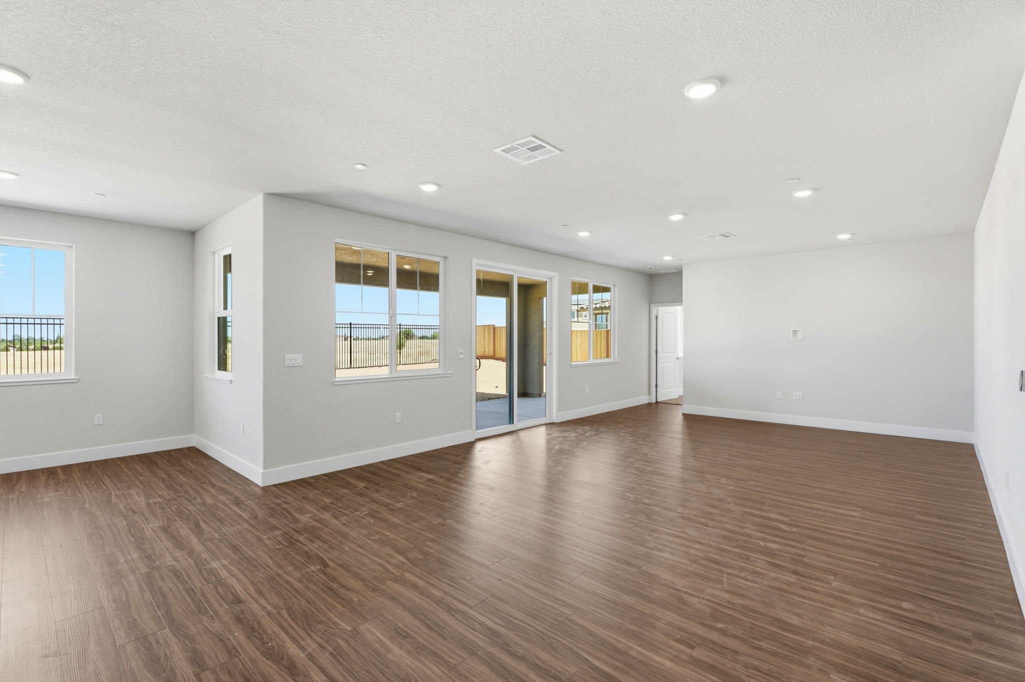 A large empty room with a wood floor and windows.
