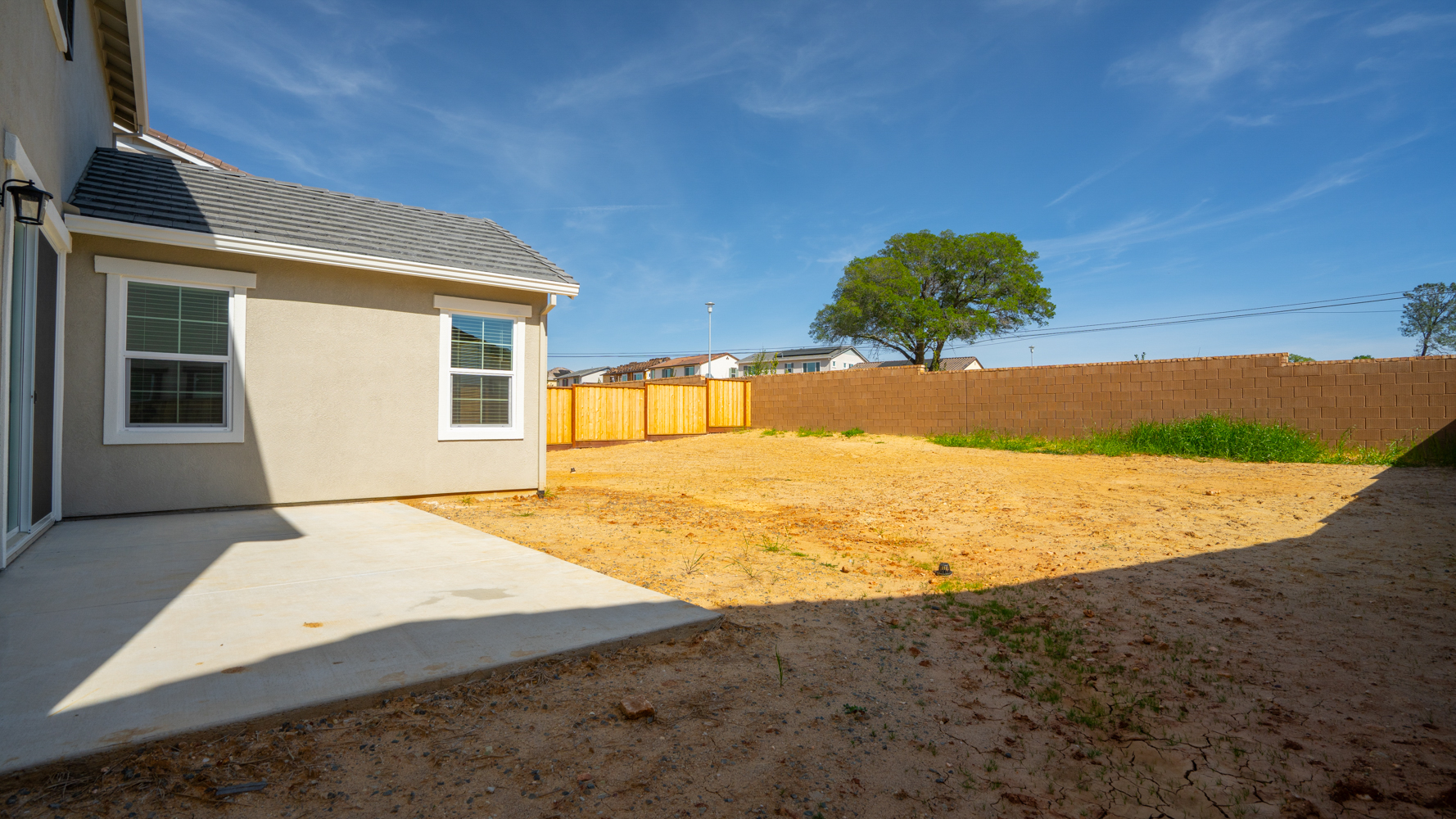 A dirt yard with a fence and a house.