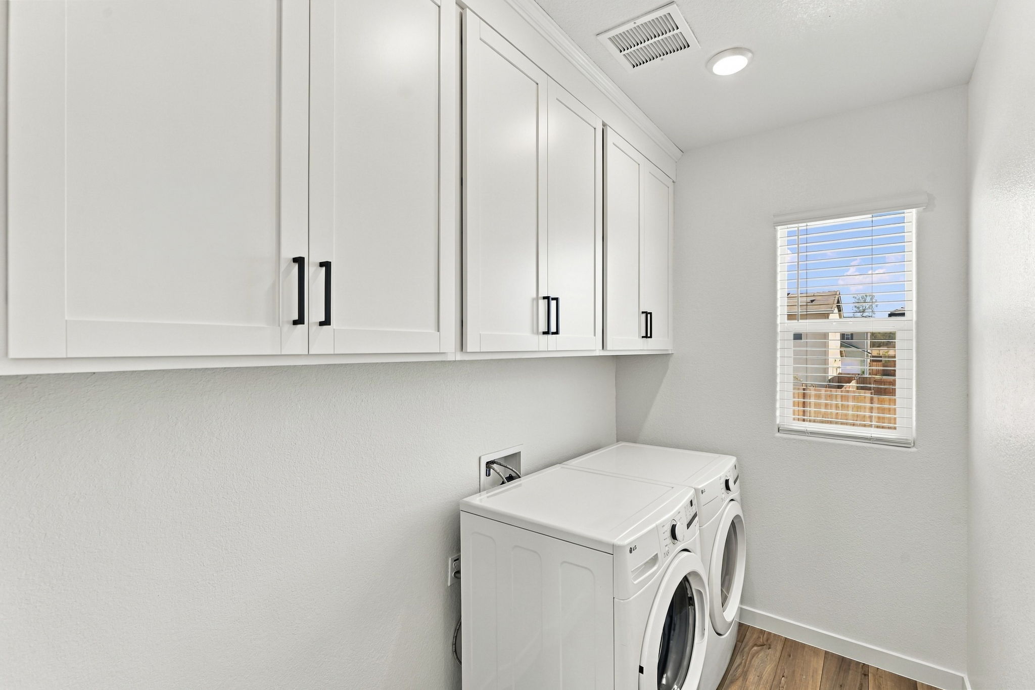 A white laundry room with white cabinets.