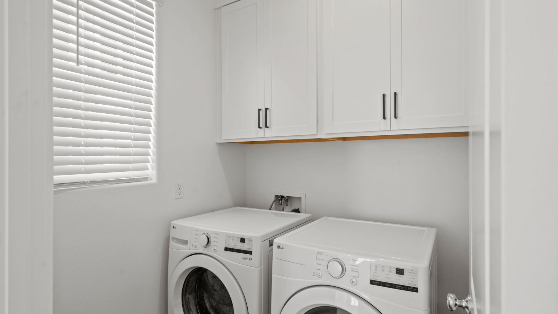 A white laundry room with white cabinets.