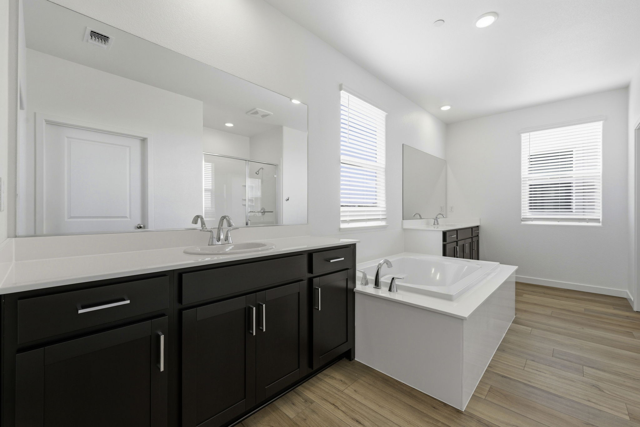 A bathroom with a tub sink and cabinets.