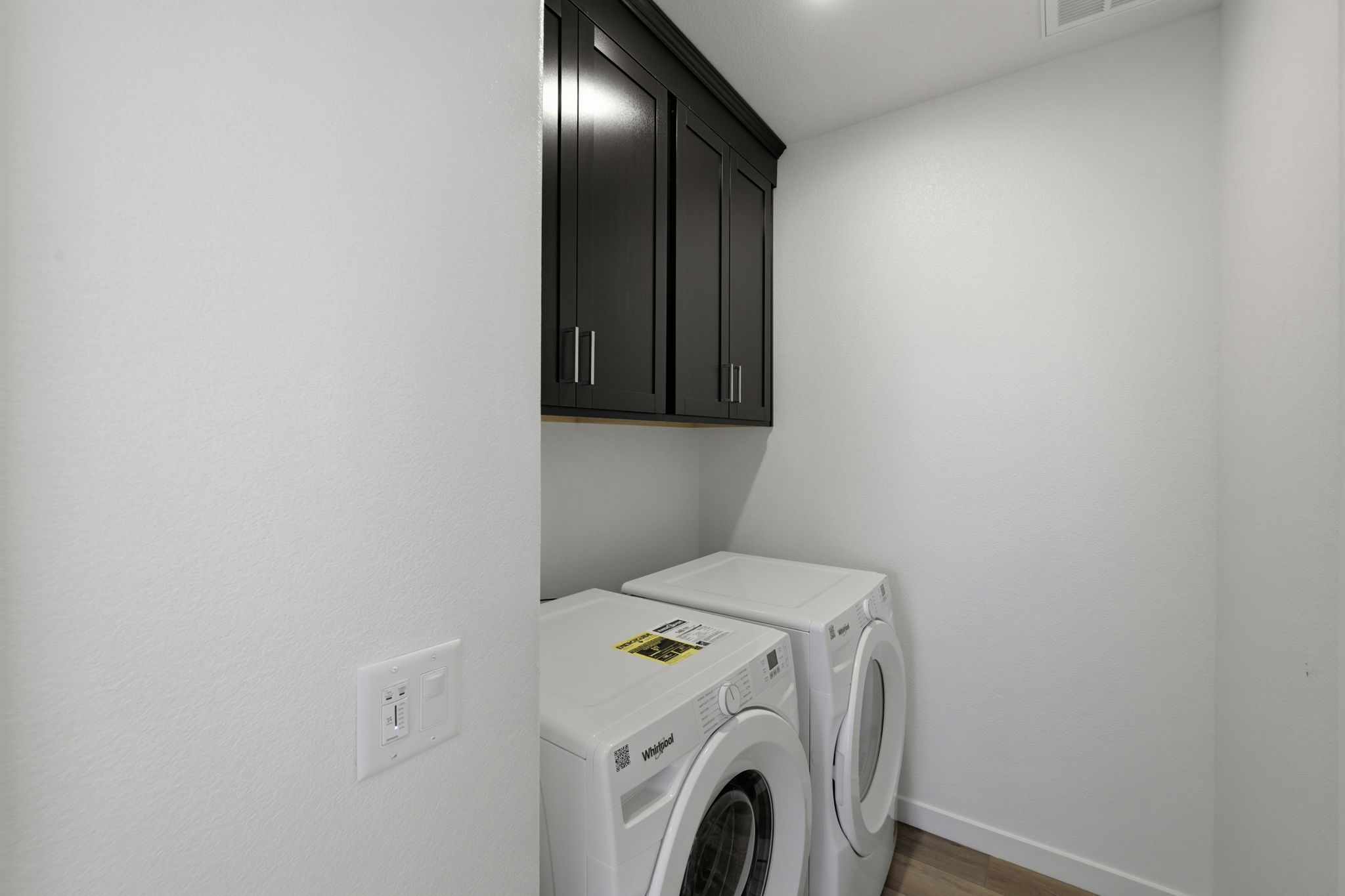 A white laundry room with a black cabinet and a dryer.