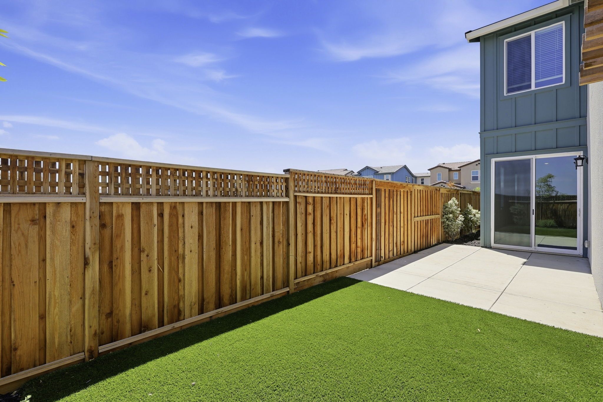 A fenced in yard with a house and a building in the background.