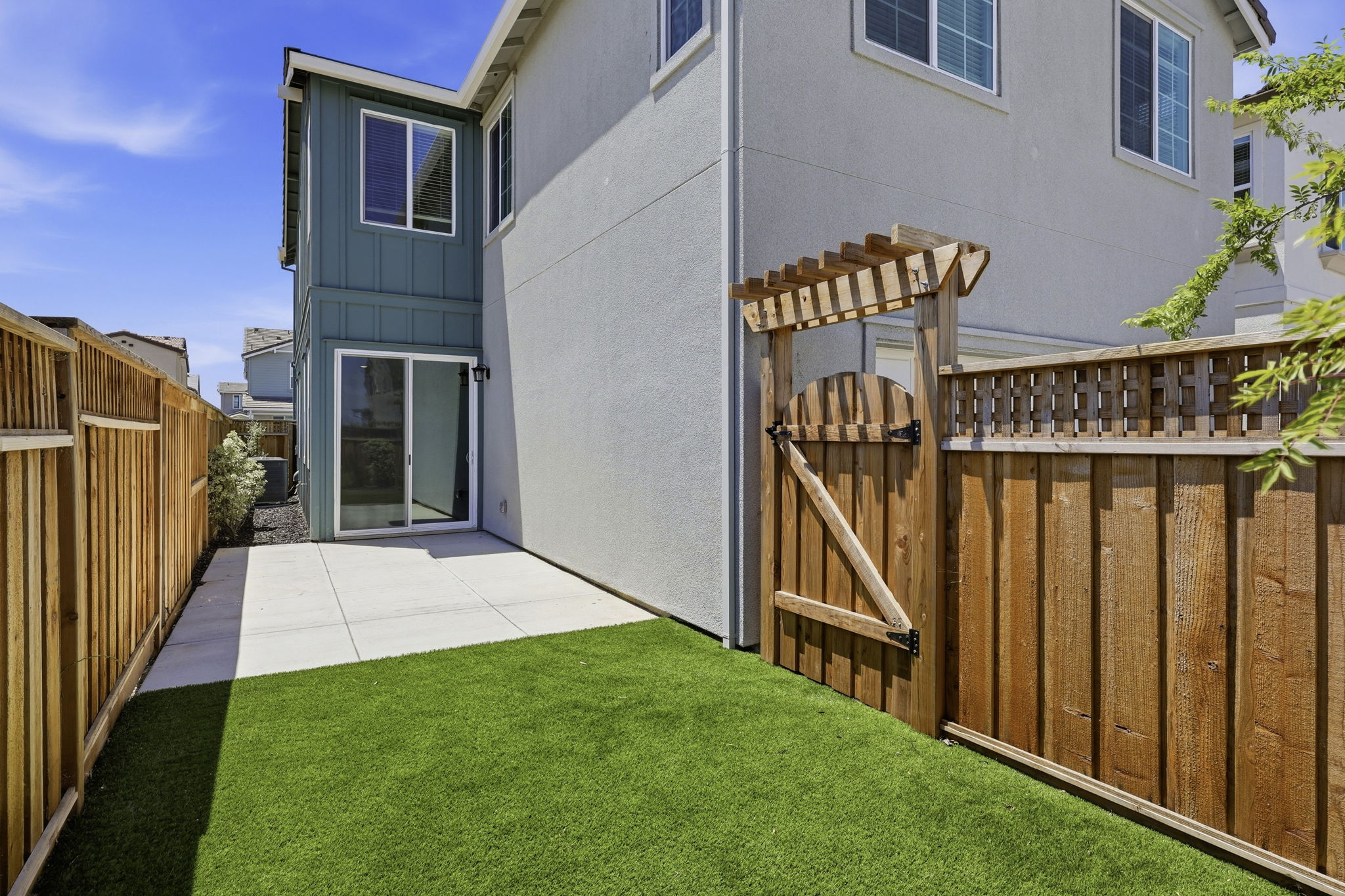 A fenced in yard with a house and a wood fence.