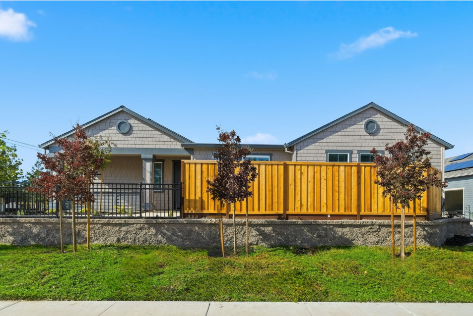 A yellow house with a fence.