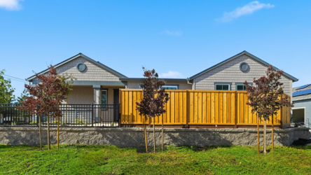 A yellow house with a fence.